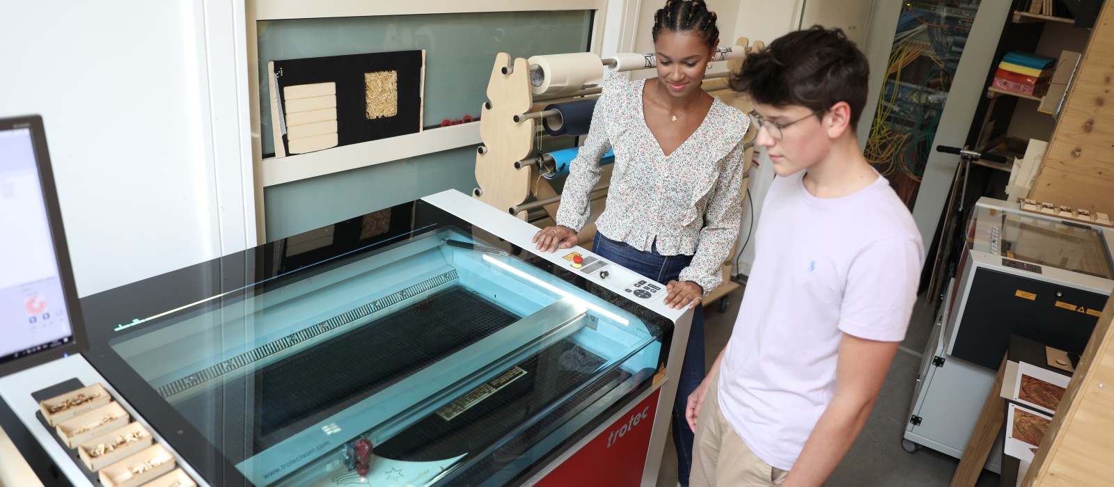 Zwei Jugendliche betrachten den Holz-Lasercutter im TechLab : 